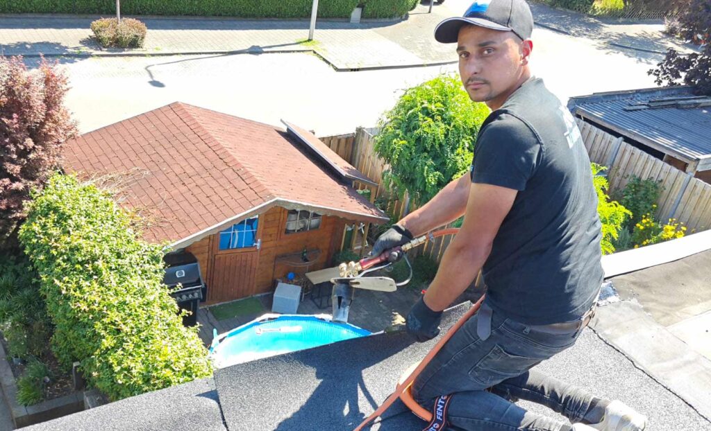 Dakdekker herstelt een lekkend plat dak met een brander